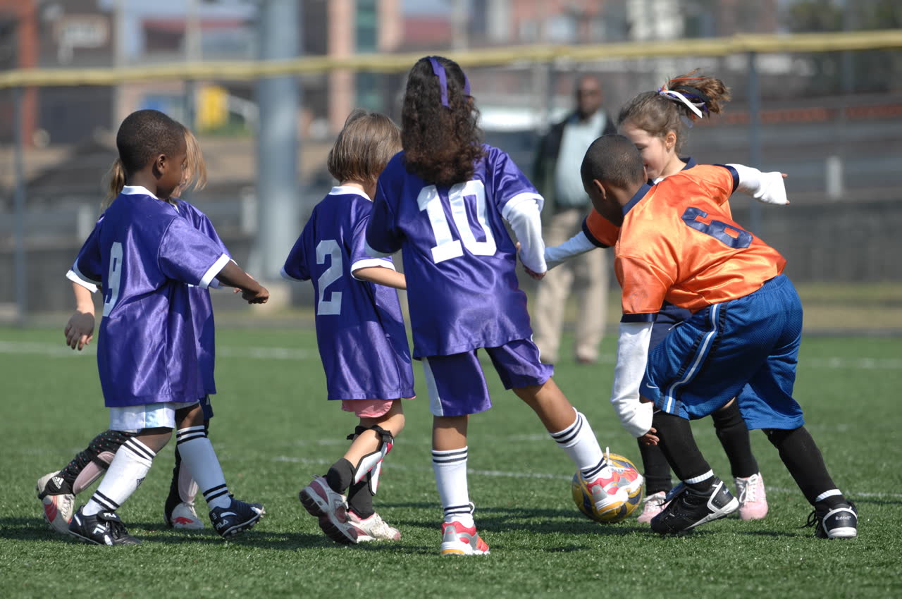 A group of children competing for the ball during a small-sided match