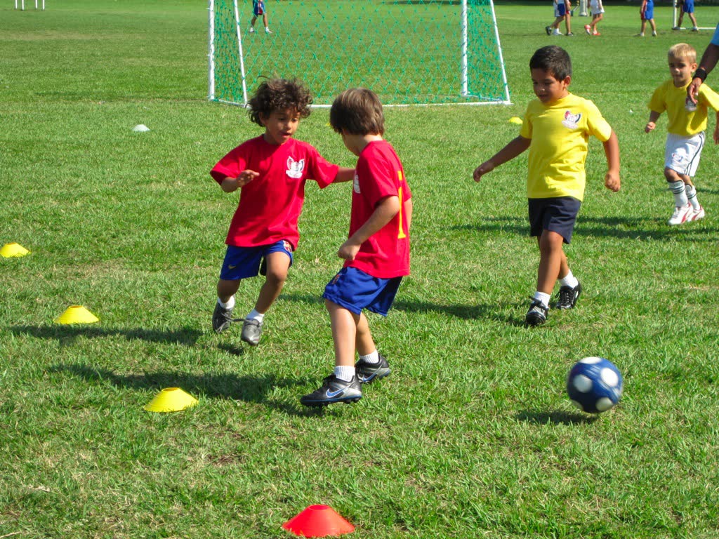 Young children dribbling between cones during a training session