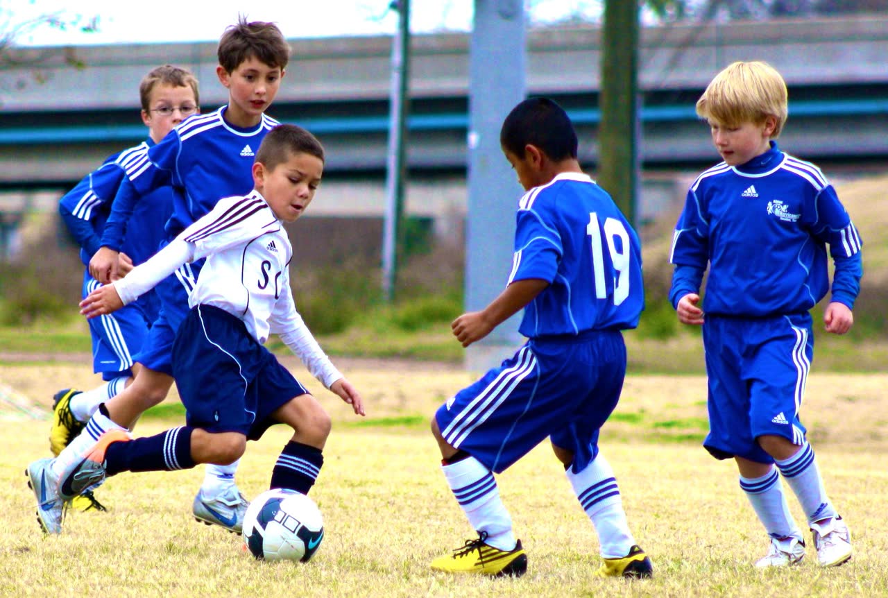 A young player dribbling through several opponents during a competitive match